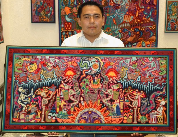 Luis Castro Huichol artist holding his yarn painting